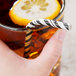 A hand holding a Creative Converting black velvet and white striped paper straw in a glass of liquid with a lemon slice.