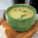 A Libbey Cantina sage porcelain bouillon bowl filled with soup on a wooden surface.