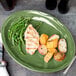 A Libbey sage green oval porcelain platter with chicken, potatoes, and green beans on a table.