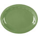 A sage green oval porcelain platter with a carved wavy design on the edge.