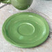 A Libbey sage green porcelain saucer under a green cup on a marble surface.