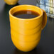 A close-up of a yellow Libbey Cantina mug with a brown liquid in it.