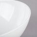 A close-up of a white Tablecraft Sierra melamine bowl with a curved edge.