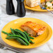 A Libbey saffron porcelain plate with a piece of salmon, green beans, and sauce.