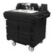 A black plastic Cambro CamKiosk portable hand sink with a double sink on a counter.