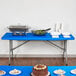 A royal blue rectangular plastic tablecloth with elastic on a table with food.