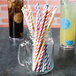 A glass jar filled with Creative Converting striped paper straws in assorted colors.