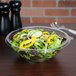 A bowl of salad with vegetables in a Fineline clear plastic bowl.