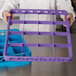 A man holding a purple plastic tray with a Carlisle lavender plastic glass rack extender.