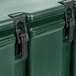 A close-up of a green Cambro insulated soup carrier with a black metal hinge.