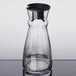 An Arcoroc clear glass fluid carafe with a black stopper.