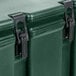 A close-up of a green Cambro insulated soup carrier with a black metal hinge.