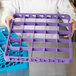 A person holding a purple Carlisle OptiClean glass rack extender tray.