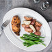 A Tuxton bright white oval china platter with chicken, potatoes, and green beans on it.