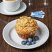 A Tuxton Pacifica bright white china plate with a muffin and blueberries on it.