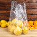 A plastic bag of lemons on a table.