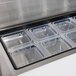 A clear plastic container with a black border holding a tray of ice cubes on a counter.