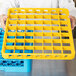 A person holding a yellow Carlisle plastic tray with 49 compartments.