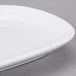 A close-up of a Libbey ultra bright white porcelain coupe platter with a small rim.