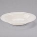 A Libbey Farmhouse ivory porcelain pasta bowl with a rim on a gray surface.