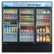 A Turbo Air three section glass door merchandising refrigerator with drinks and beverages inside.