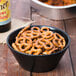 A bowl of Snyder's of Hanover mini pretzels next to a bottle of beer.