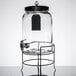 A Stylesetter glass beverage dispenser with a metal stand.