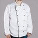 A man wearing a white Chef Revival chef coat with black piping.