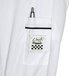 A white Chef Revival long sleeve chef coat with black piping and a pocket holding a pen.