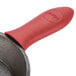 A red silicone handle cover with a handle on a black pan.