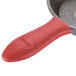 A red silicone handle holder with a small handle on a pan.
