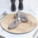 A Charge It by Jay faux wood charger plate with silverware and a napkin on it.