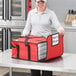 A woman holding a red Choice insulated pizza delivery bag with white pizza boxes inside.