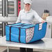 A woman holding a blue Choice insulated pizza delivery bag with white pizza boxes inside.