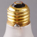 A close up of a Satco frosted incandescent light bulb with a gold cap.