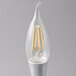 A close-up of a Satco clear LED light bulb with a candelabra base and a filament inside.