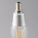 A close-up of a Satco clear LED light bulb with a silver base.