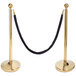 A black rope with brass ends attached to a gold stanchion.