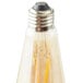 A close-up of a Satco transparent amber LED light bulb with a yellow filament and silver cap.