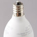 A close-up of a Satco clear warm white LED light bulb with a candelabra base.