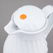 A white Vollrath SwirlServe hot and cold beverage server with a round orange button on the lid.