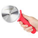 A hand holding a Dexter-Russell Sani-Safe red and black plastic pizza cutter.