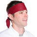 A man wearing a burgundy chef neckerchief on his head.