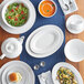 A table set with Acopa white rolled edge stoneware cups, plates, and bowls of food.