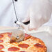A person cutting a pizza with a Mercer Culinary Millennia pizza cutter.