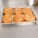 A Vollrath aluminum bun pan with a tray of croissants on a counter.