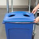 A hand putting a blue Rubbermaid Slim Jim recycling container lid on a blue container.