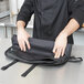 A person in a school kitchen holding a Dexter-Russell V-Lo 7-piece cutlery set in a black bag.