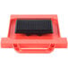 A black square Prince Castle dicer pusher head on a red plastic surface.