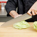 A person using a Dexter-Russell V-Lo chef knife to cut lettuce on a counter.